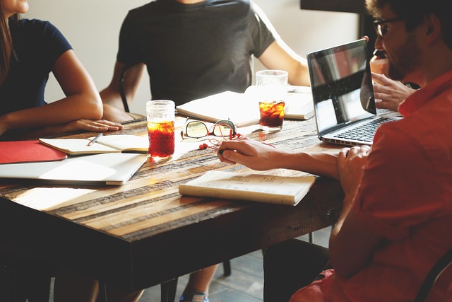 Grupo pequeño de personas colaborando en una mesa de trabajo con notas adhesivas y bocetos de ideas